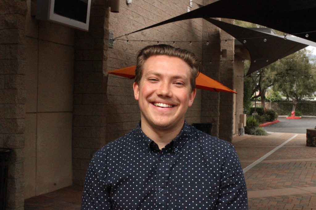 Adam, smiling warmly outdoors